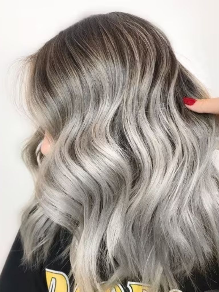 Close-up photo of a woman with shoulder-length wavy ash grey silver hair