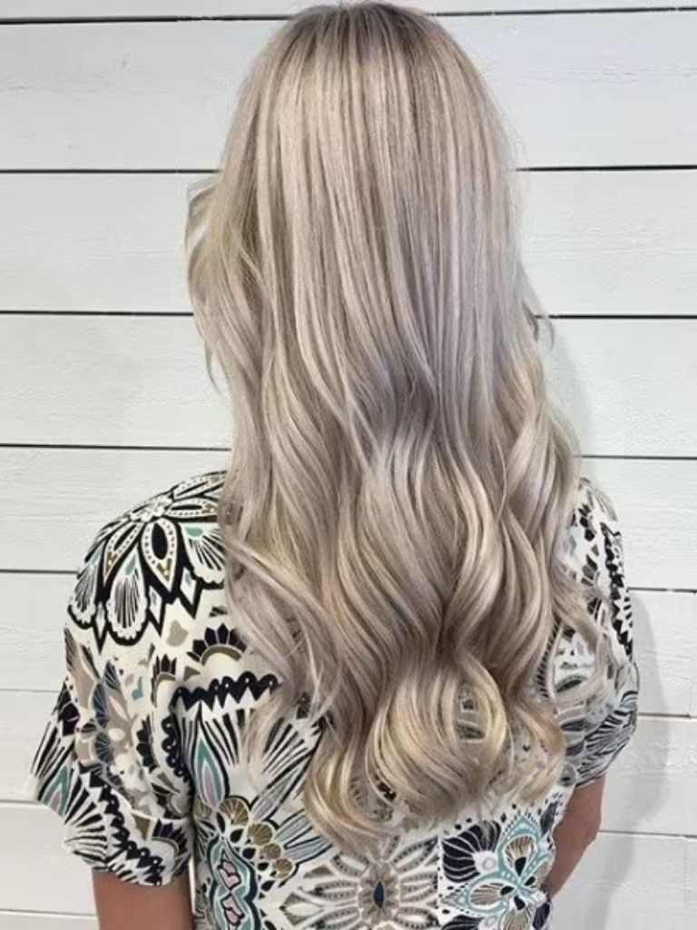 Back view of a woman with long creamy blonde waves, wearing a patterned top