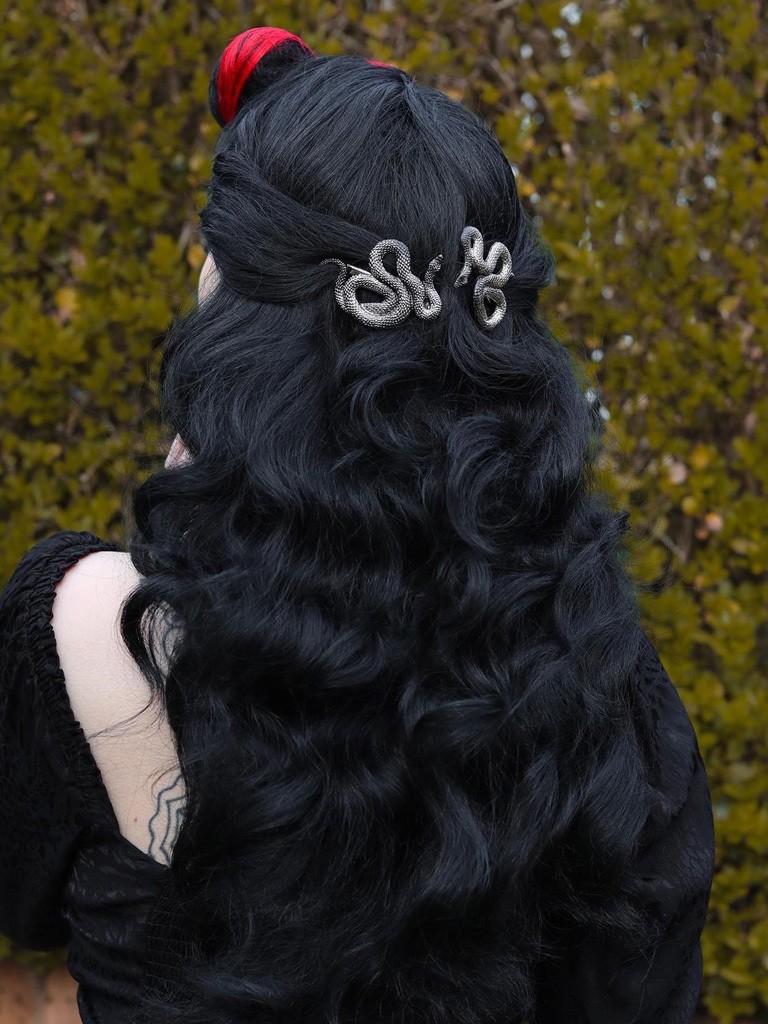 Woman with vintage hairstyle seen from rear. Hair clasped with silver clips. Two red highlights on bouffant wave.