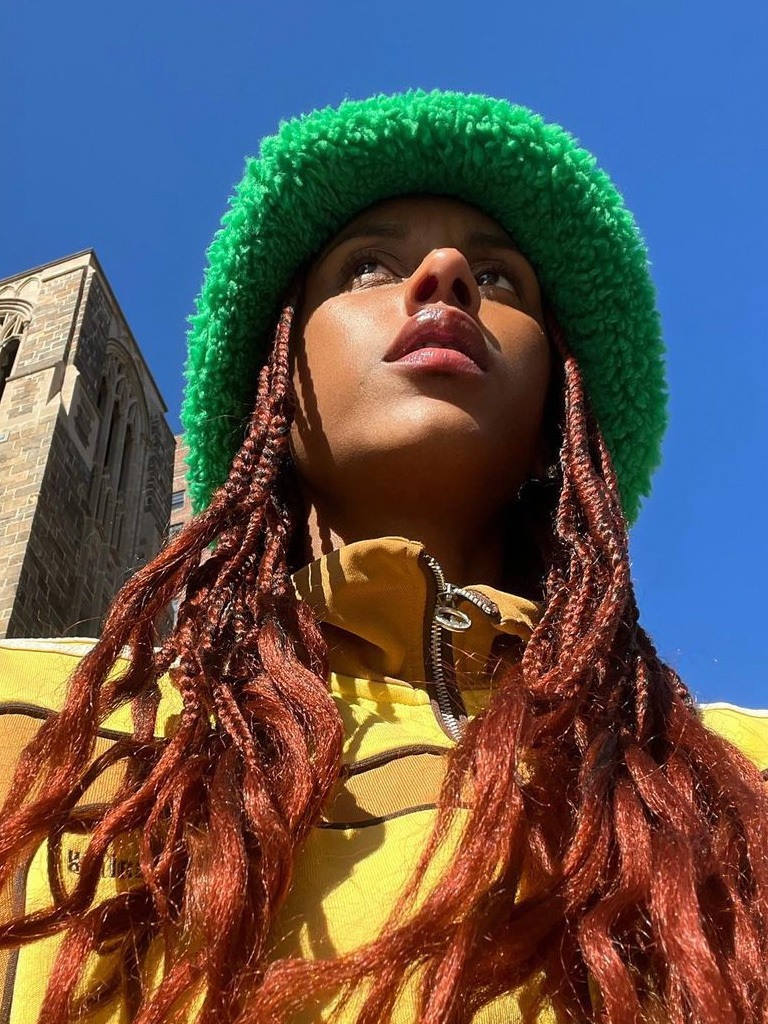 Woman with beautiful black and red box braids with curly end. Wearing a green hat
