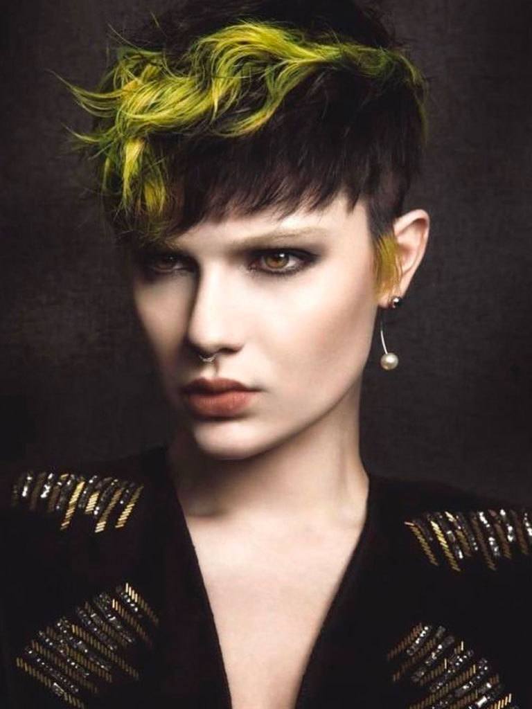 Woman with mushroom cut with longer green streak and sideburns, brushed forward