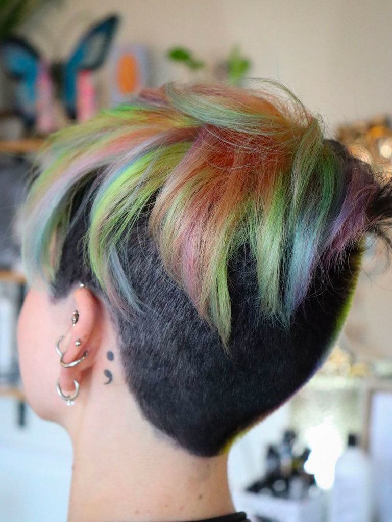 Woman with mushroom cut hair with long colourful bits on top, with dark brown short cropped undercut