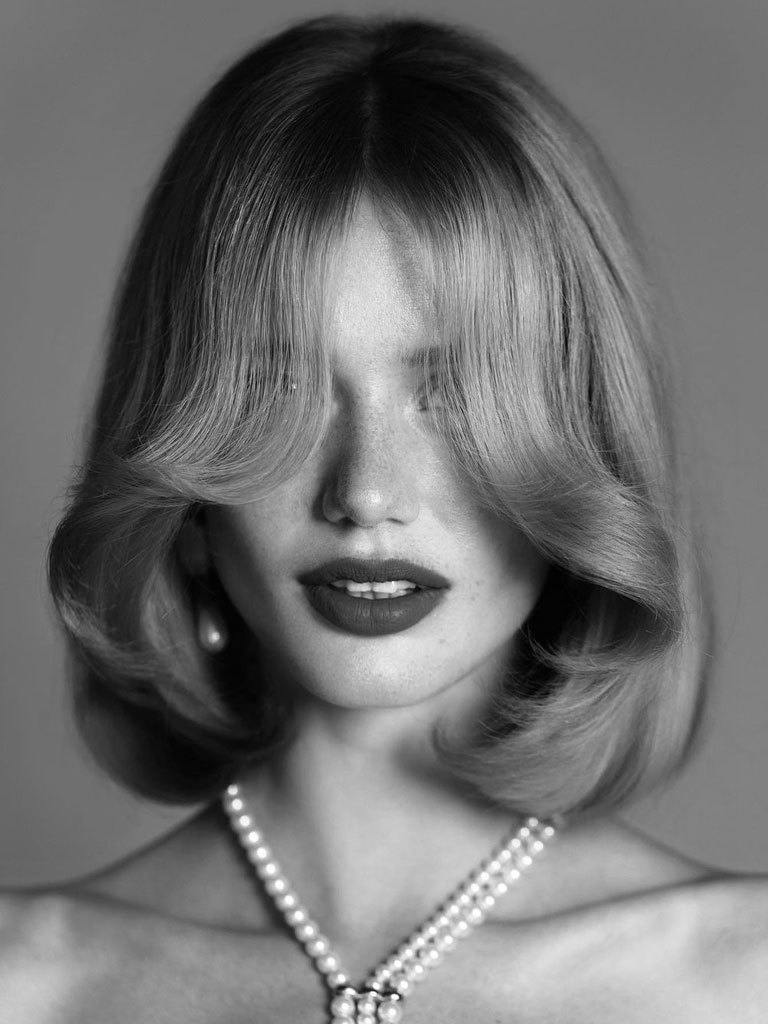front view image of a woman with a long curtain fringe and lob mushroom hairstyle