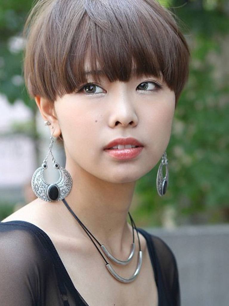 Woman with softly feathered bowl haircut skimming her eyes