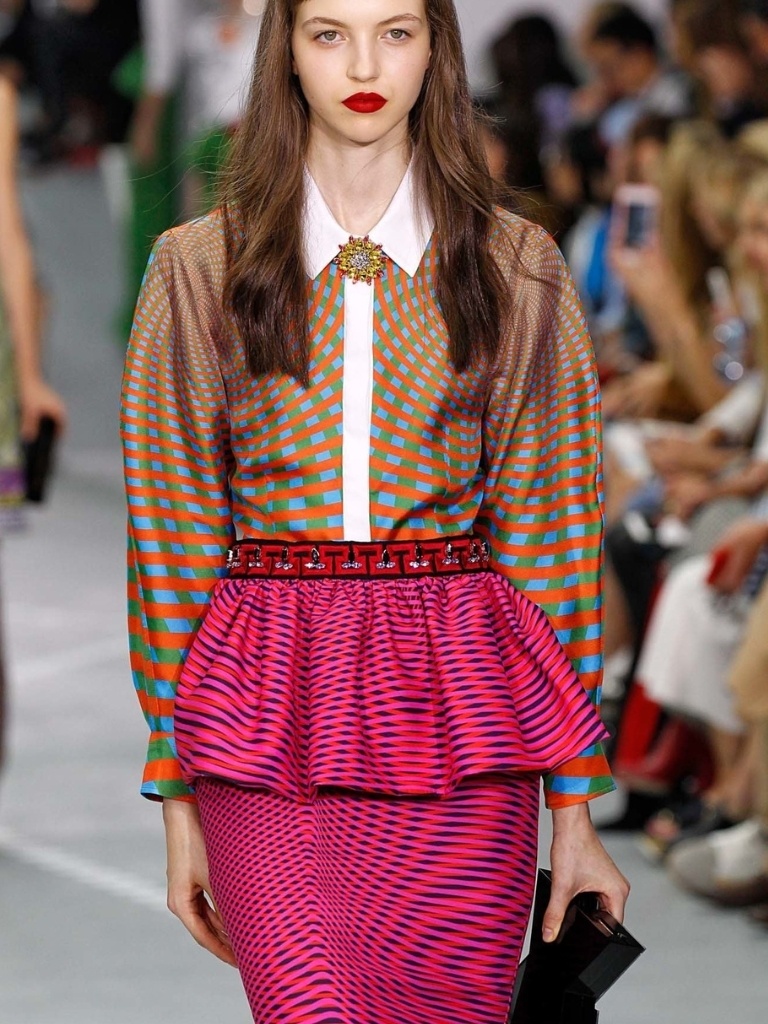 Short bangs: Model with long wavy brown hair and short micro fringe wearing a pattern shirt and skirt.