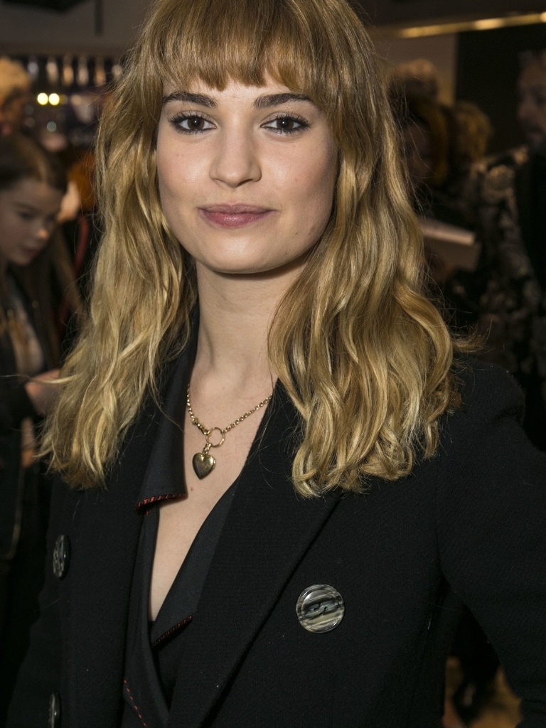 Short bangs: Lily James with medium length wavy blonde hair with short bangs.