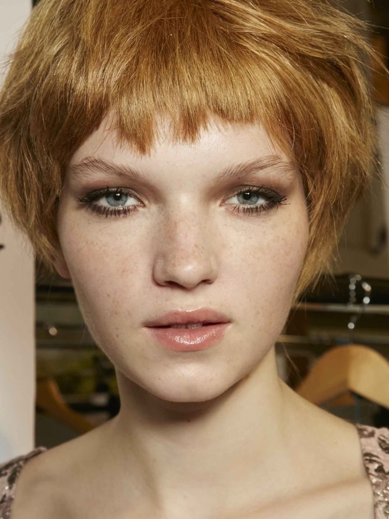 Short bangs: Model with short choppy strawberry blonde hair and micro bangs.