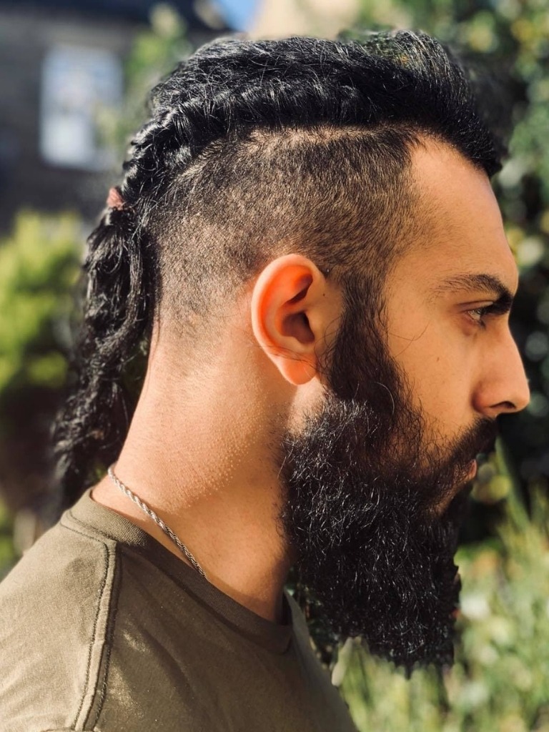 Viking Hairstyles: Man with dark brown thick hair with twisted braid and undercut with thick rugged beard
