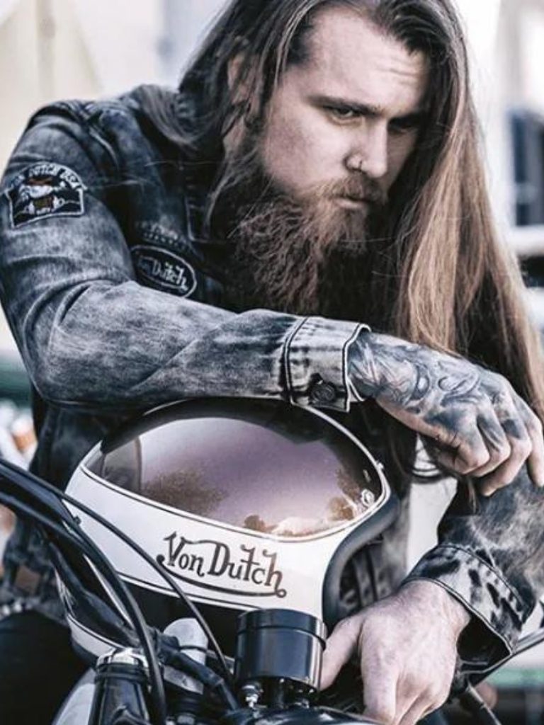 front view image of a man on a motorbike with long hair and a full beard