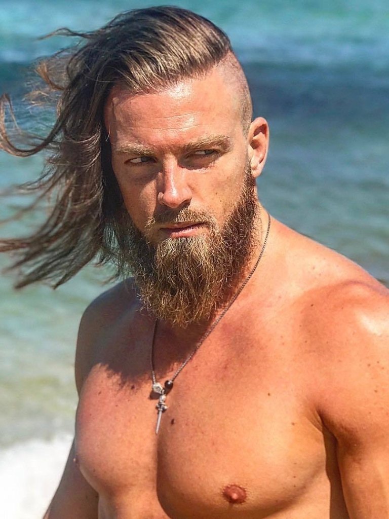 Viking Hairstyles: Man with rugged light brown hair with undercut and messy beard, wearing necklace