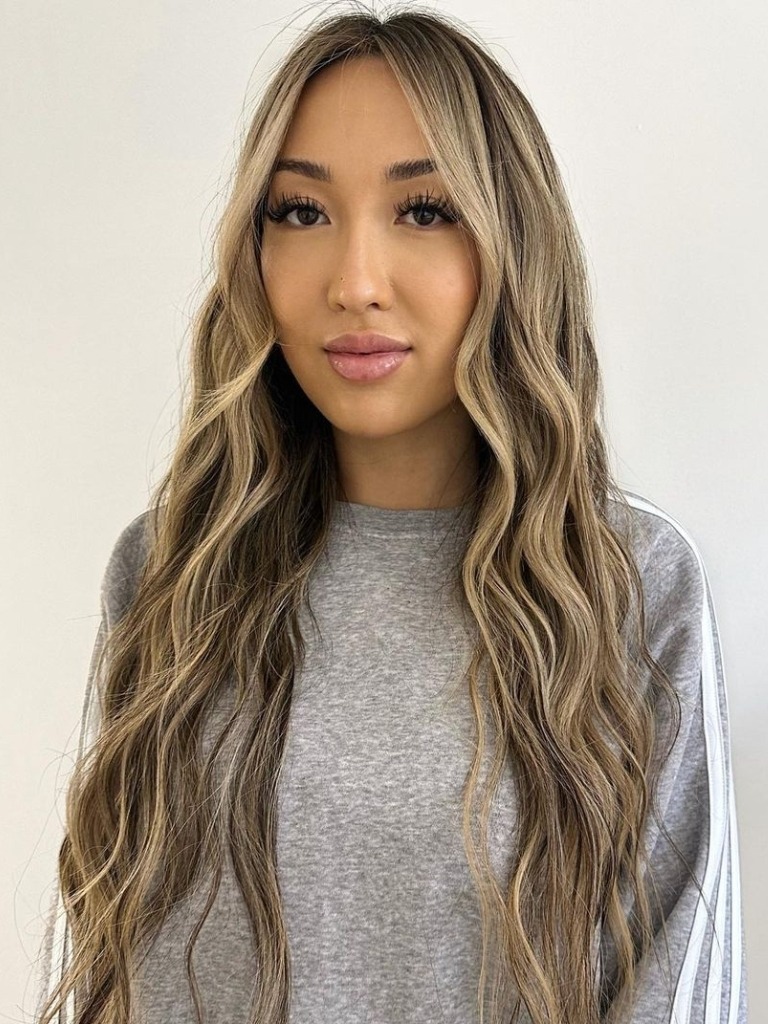 Woman with ash blonde face framing highlights on long wavy hair
