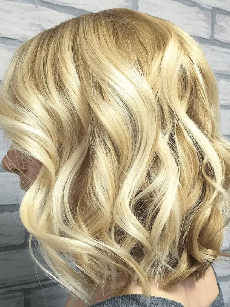 side view of a woman's hair with blonde waves in a blonde bob