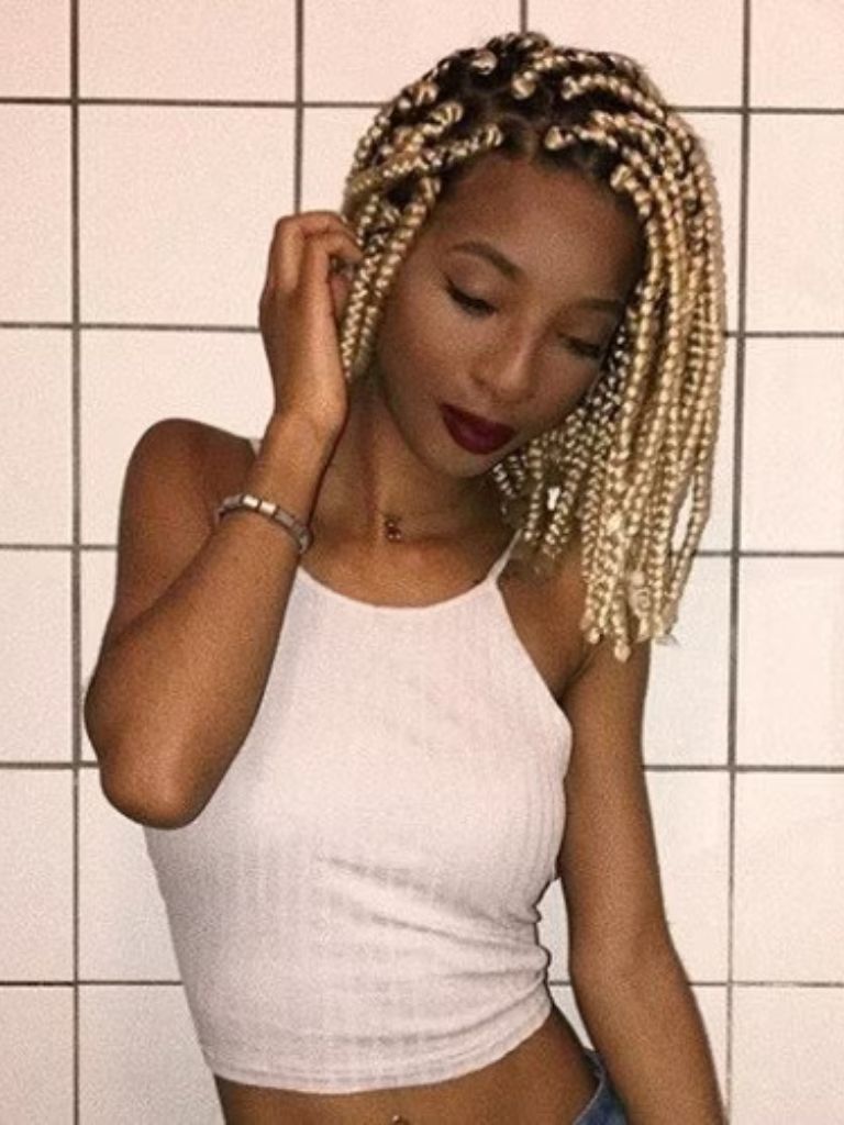 close up shot of woman with blonde box braids bob style, wearing white shirt and blue jeans