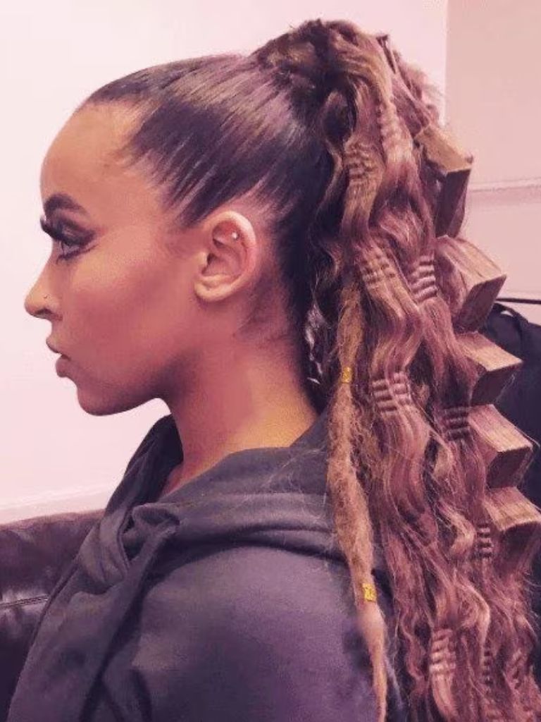 Crimped hair: Woman with long brown hair in high ponytail with large crimped waves wearing a hooded top.