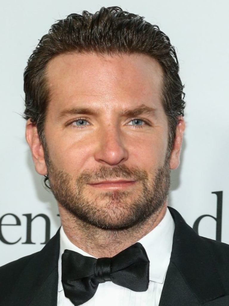 Hairstyles for receding hairline: Headshot of Bradley Cooper with combed back dark flow hair, wearing a tux and black bow tie
