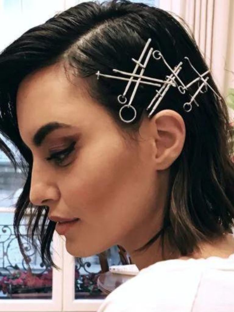 Woman with short dark brown hair in a side-parting with bobby pins
