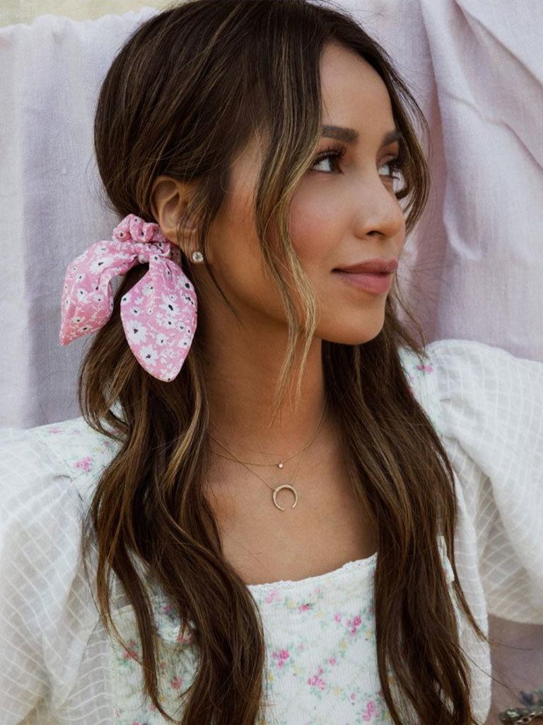 Woman with long brown hair in low pigtails with scunchy ribbons