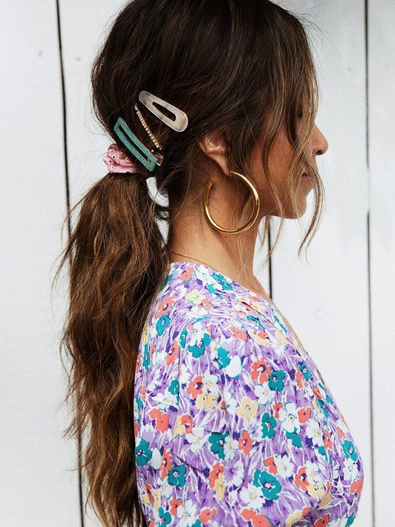 Woman in profile with long brown hair done in loose ponytail, with different hair slides