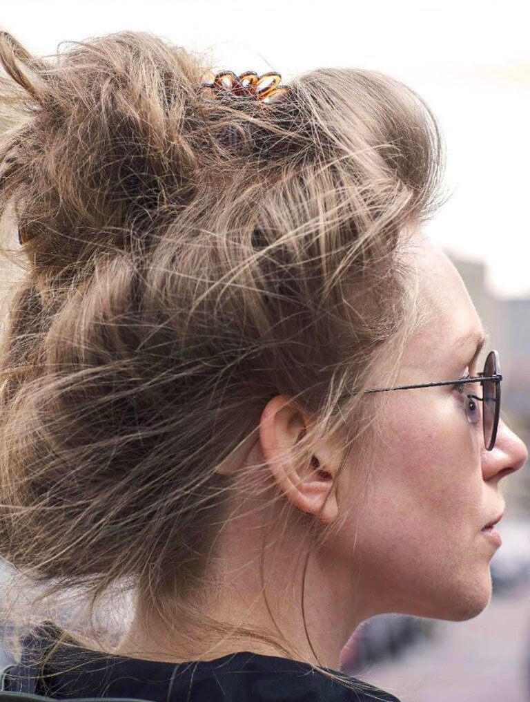 Easy hairstyles for long hair: Woman with long dark blonde hair in a messy bun updo wearing sunglasses.