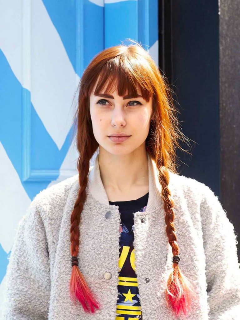 Easy hairstyles for long hair: Woman with long auburn brown hair styled in braided pigtails with neon pinks tips.