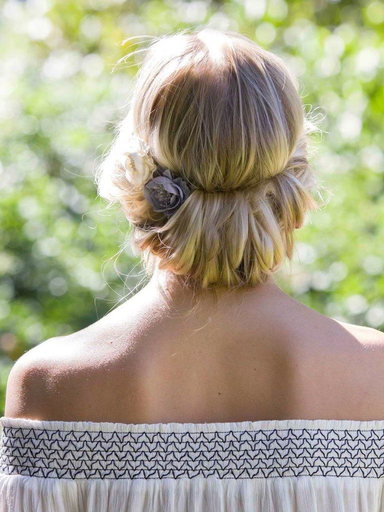 Easy hairstyles for long hair: Woman with long blonde hair styled in a headband chignon wearing a summer top.