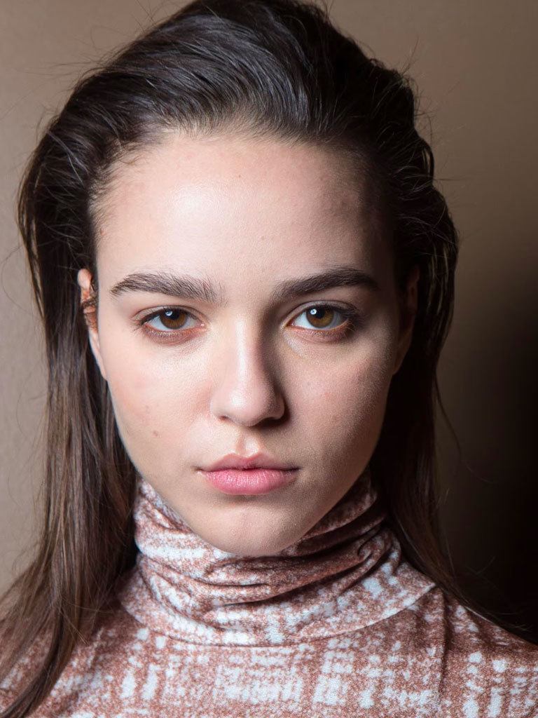 Easy hairstyles for long hair: Woman with long brown hair swept over to the side.