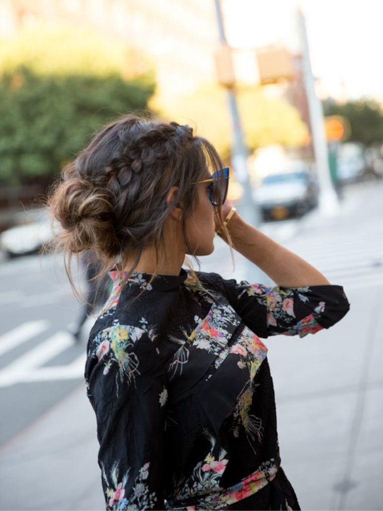 Updos with braids: Side shot of a woman with chocolate brown hair styled into a low bun with a diagonal Dutch braid.