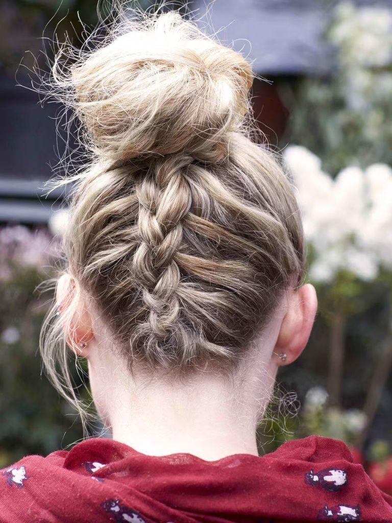 Updos with braids: Back shot of woman with dirty blonde hair styled into an upside down Dutch braided bun.