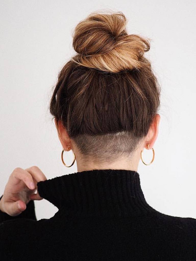 Woman with high bun and undercut shaved nape seen from rear