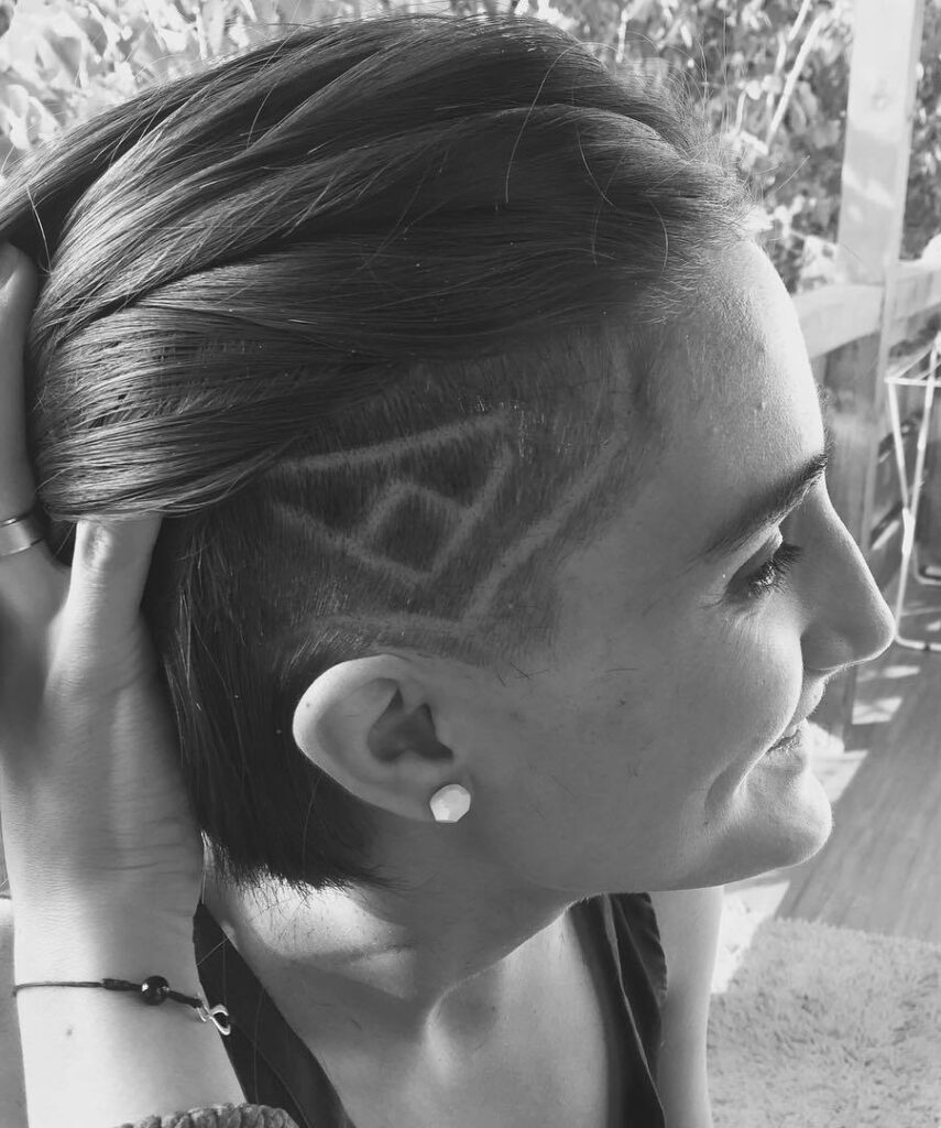 Black and white pic of woman with hidden detail undercut holding up her hair to reveal detail