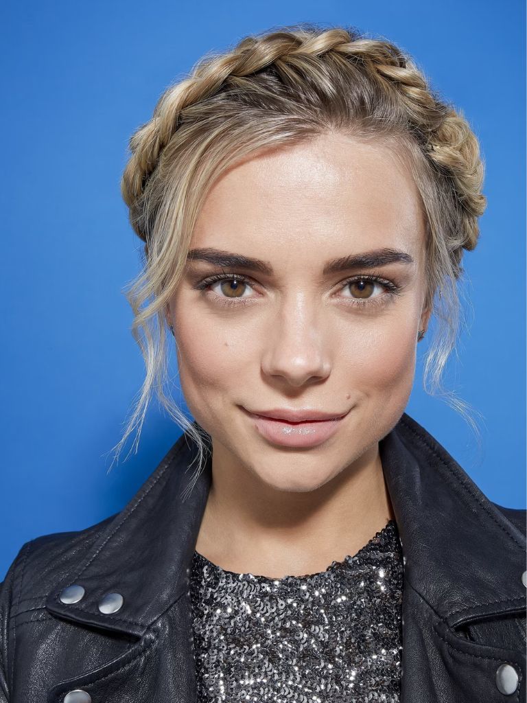 Updos with braids: Close up shot of a woman with natural blonde hair styled into crown braid updo.