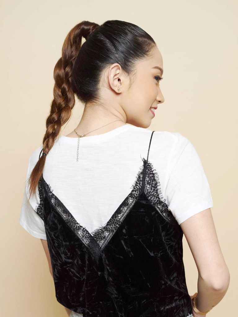 Updos with braids: Side shot of a woman with dark brown ombre hair styled into a four strand braided ponytail.