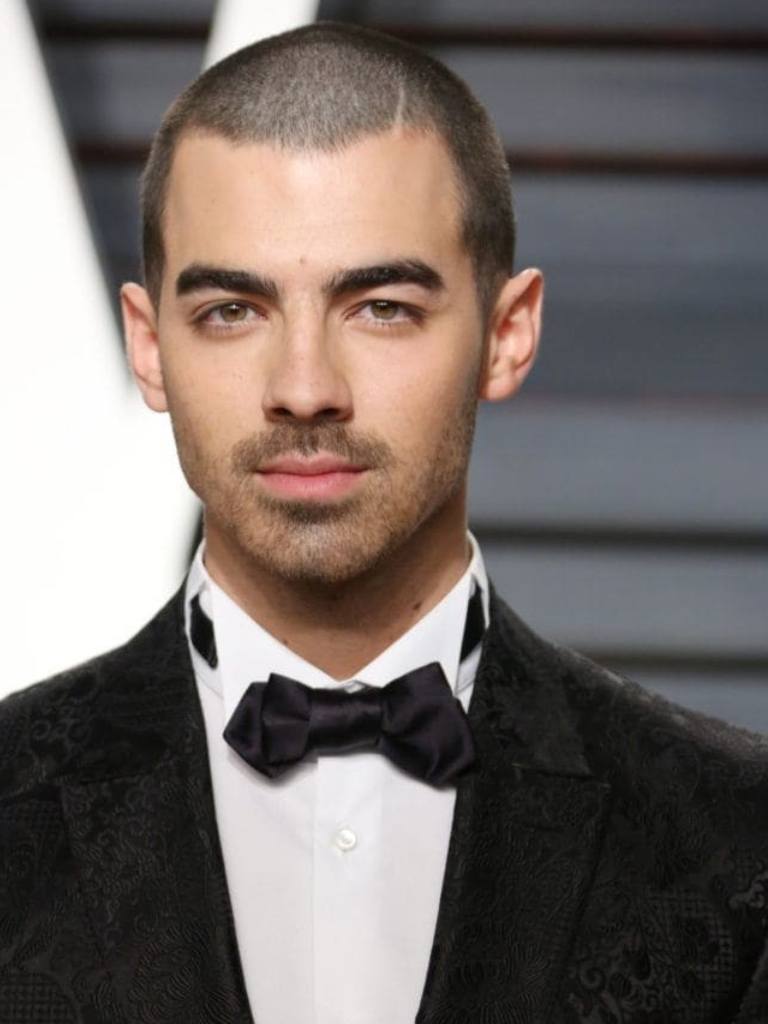 joe jonas in a tuxedo with brunette buzz cut hair