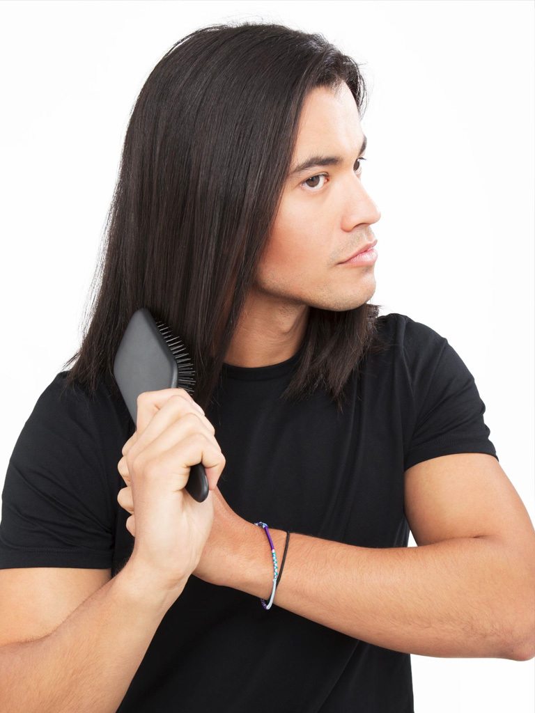 Dark haired man brushing his dark brown hair