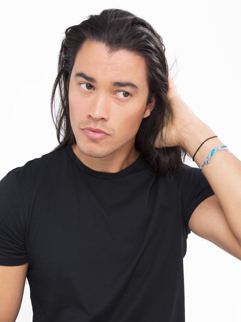 Dark haired man applying product to his dark brown hair