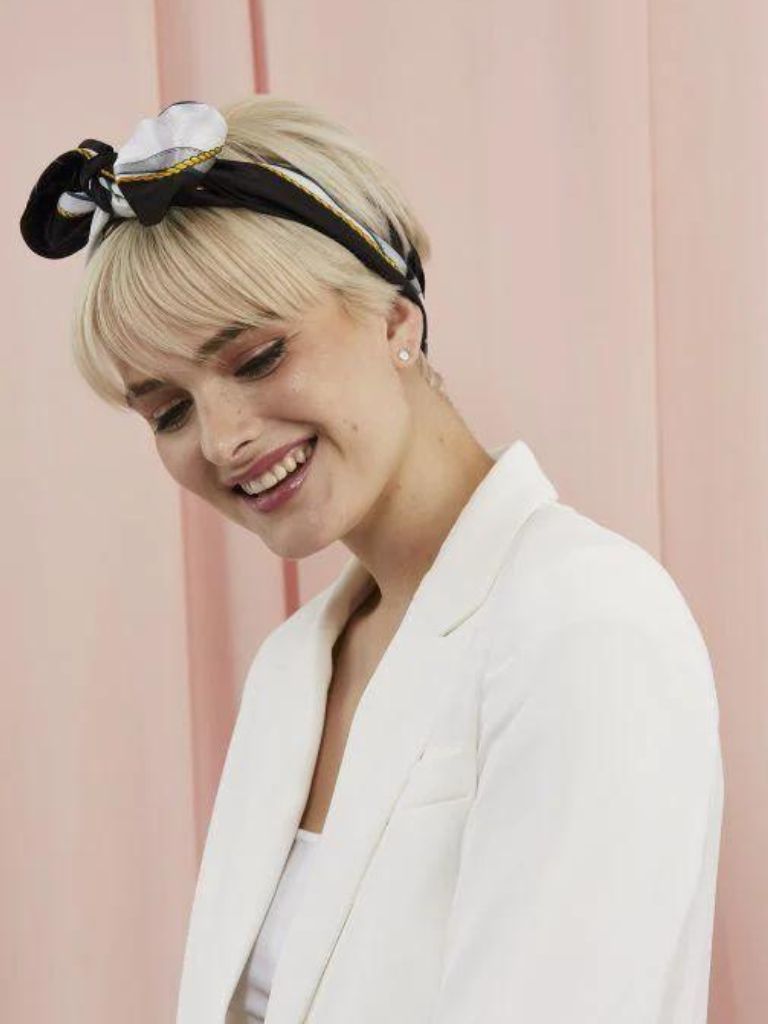 Woman with a platinum blonde pixie cut with a scarf tied around