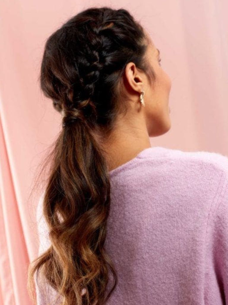 Brunette woman with a braided curly low ponytail