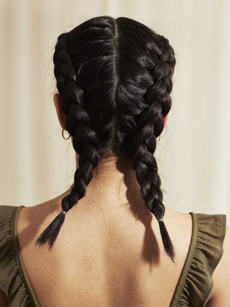 Woman with medium length dark brown hair styled into dutch braids