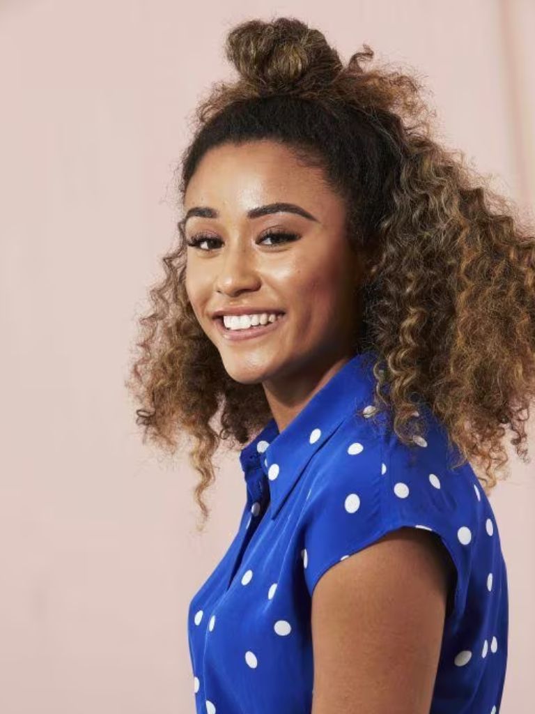 Woman with curly medium length styled into a half-up look