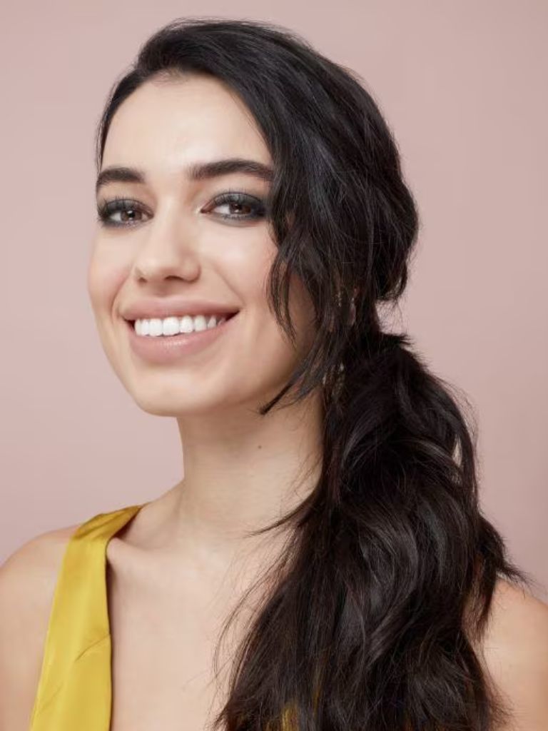 Woman with dark brunette hair in a messy low side ponytail