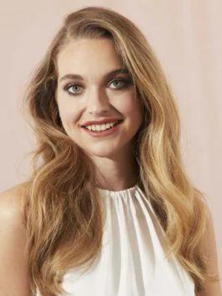 Woman with golden blonde hair styled into a wavy blow dry