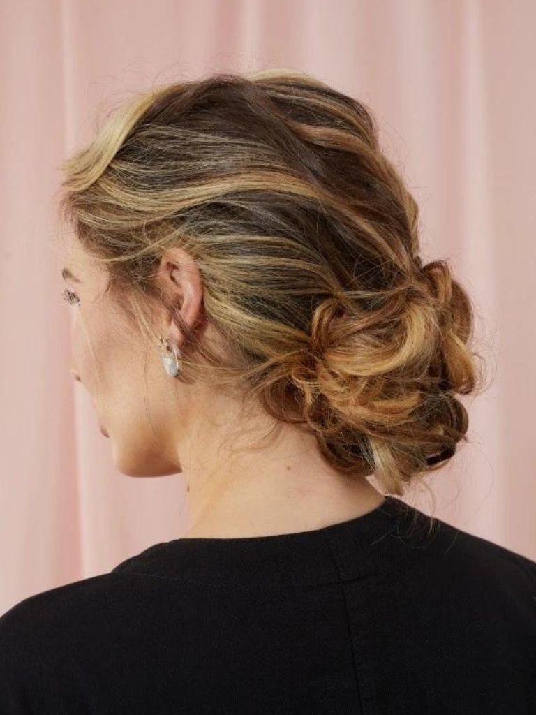 Woman with bronde highlighted hair in a retro curly chignon