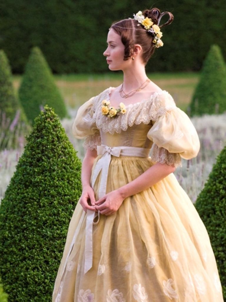 Victorian hairstyles: Film shot from The Young Victoria of a young Queen Victoria wearing a braided updo with yellow flowers and curly ringlets, wearing a yellow dress