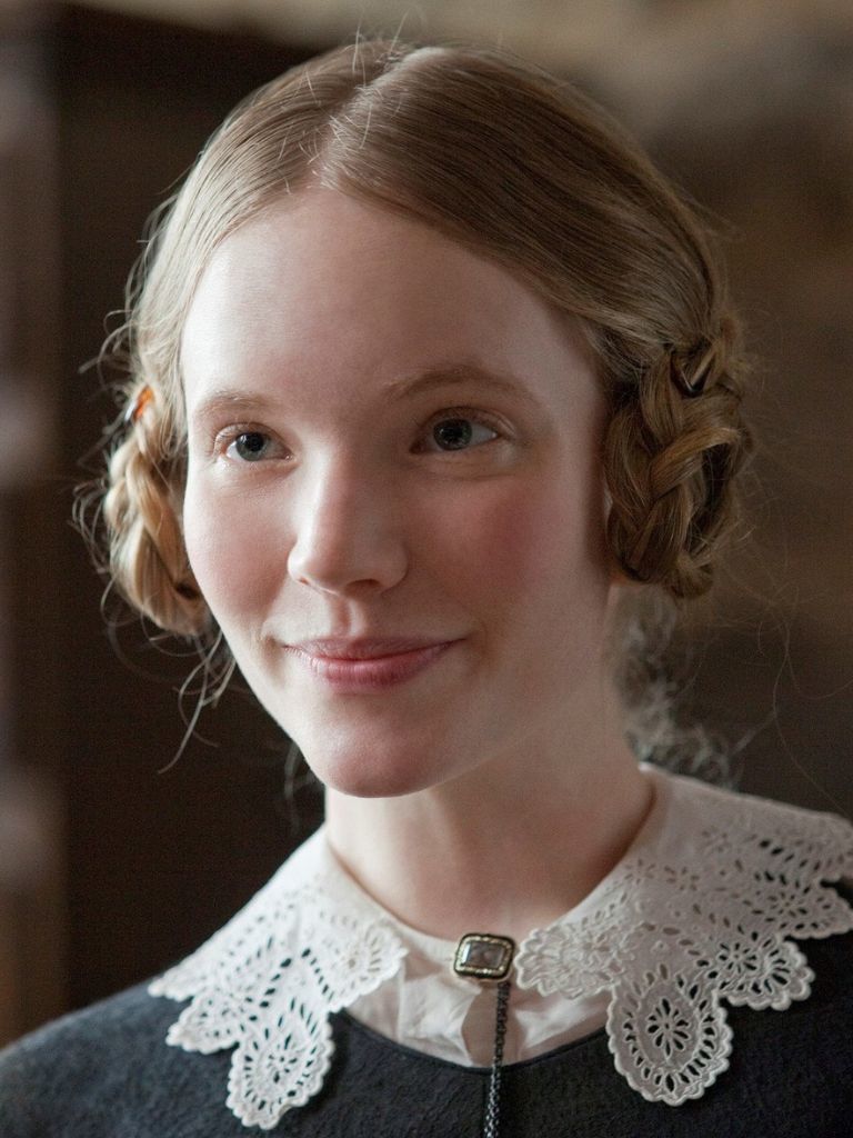 Victorian hairstyles: Close-up of Mia Wasikowska as Jane Eyre with light strawberry blonde hair in period dress with braided buns and a simple middle parting