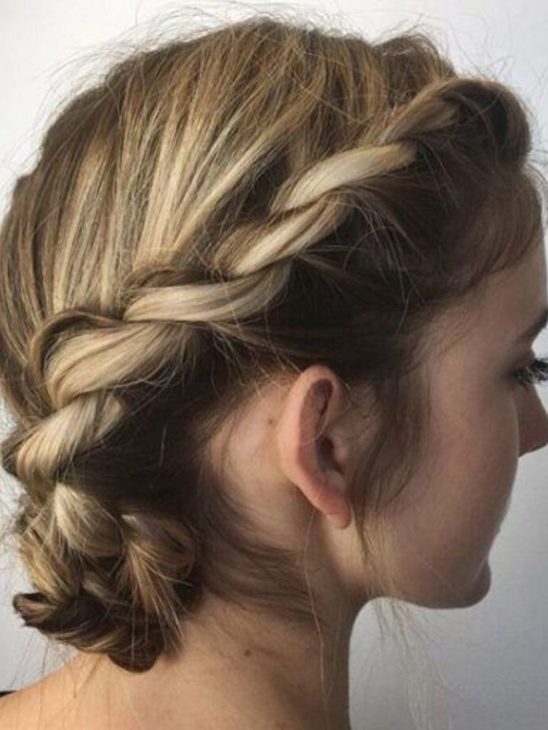Easy braids for short hair: Side profile of a woman with dark blonde hair styled in a twisted braided bun.