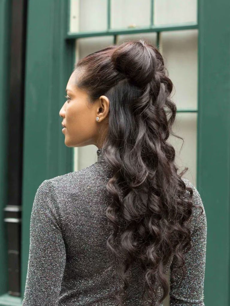 Club hairstyles: Back view of a girl with long curly brunette hair in a half-up bow hairstyle