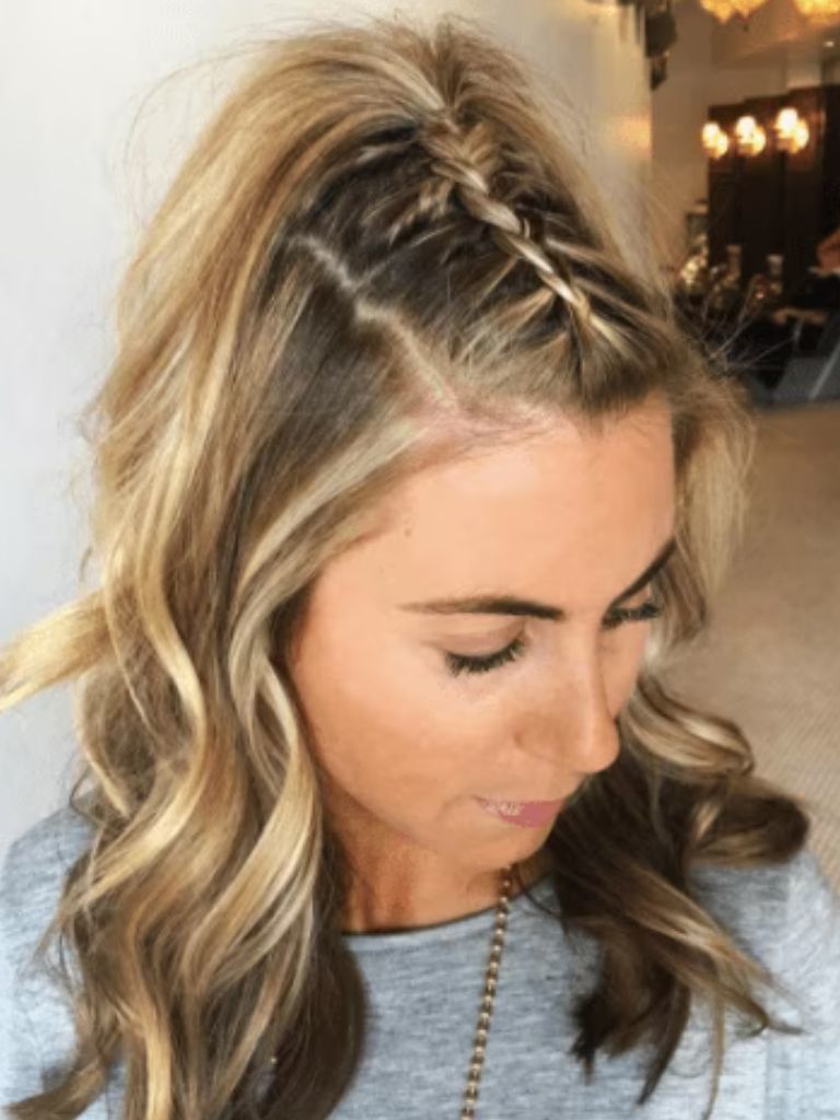 Club hairstyles: Photo from above of a blonde with shoulder length curly hair in a unicorn braid hairstyle