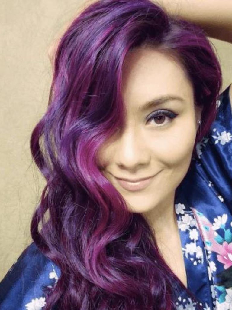 Club hairstyles: Woman with long wavy purple highlighted hair swept over one shoulder