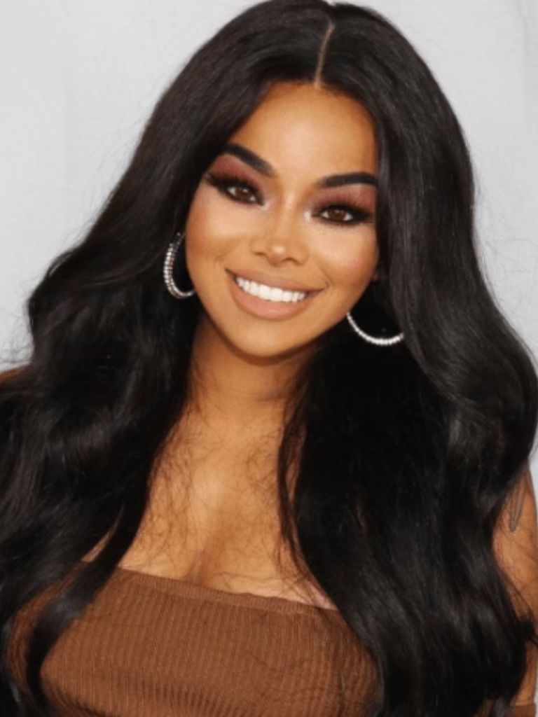Club hairstyles: Front view image of a woman with dark hair and big voluminous curls wearing a brown top and gold hoop earrings