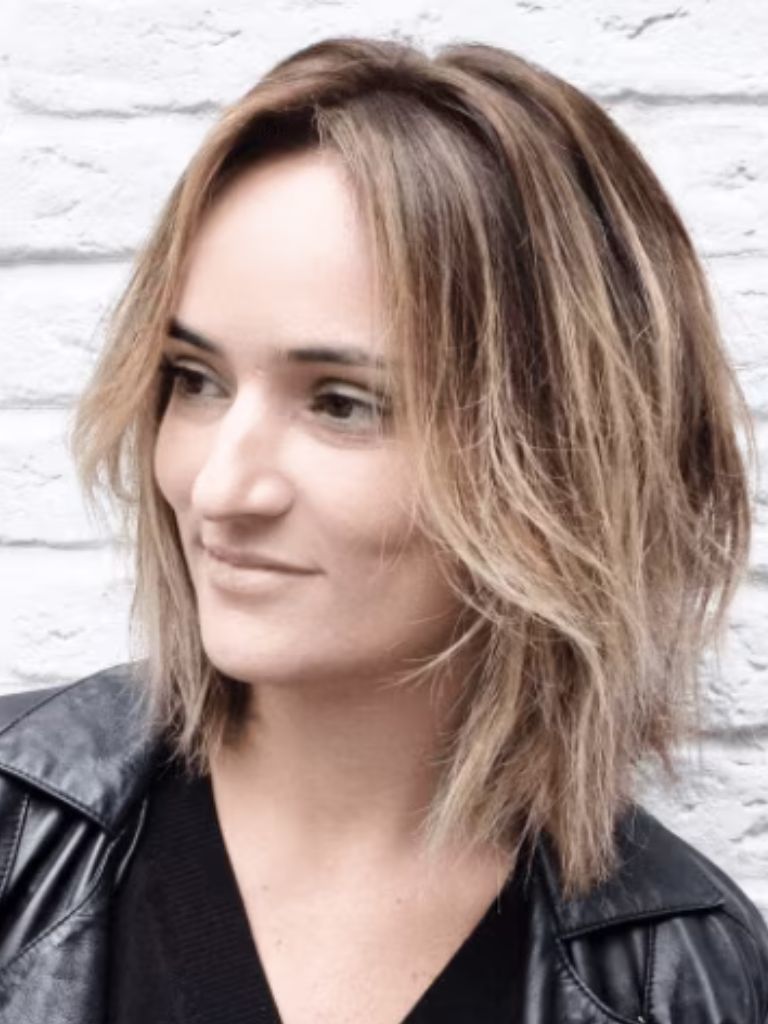 Club hairstyles: Front view of a woman with blonde messy bob hair cut, wearing a black leather jacket